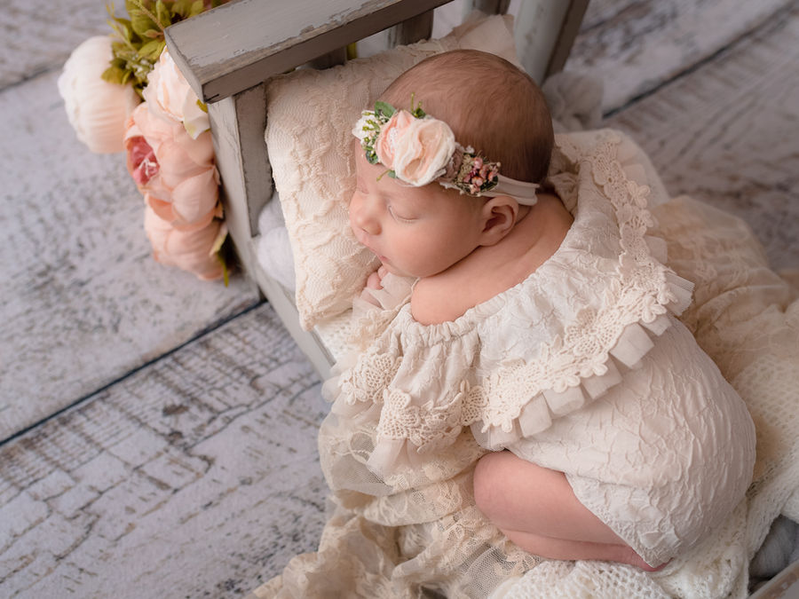 Sleeping newborn in a cream lace outfit with soft flowers